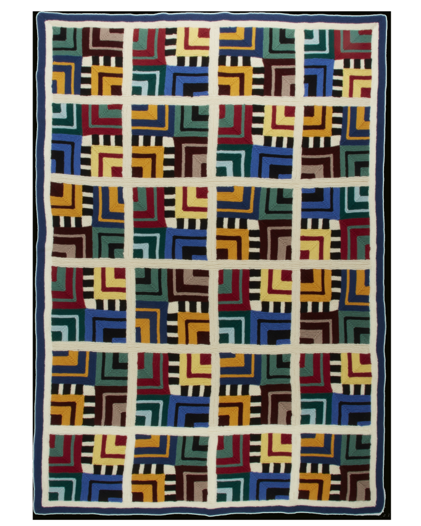 A knitted blanket featuring geometric shapes in various colors. The Wonky Walking blanket is a design by Margaret Holzmann.
