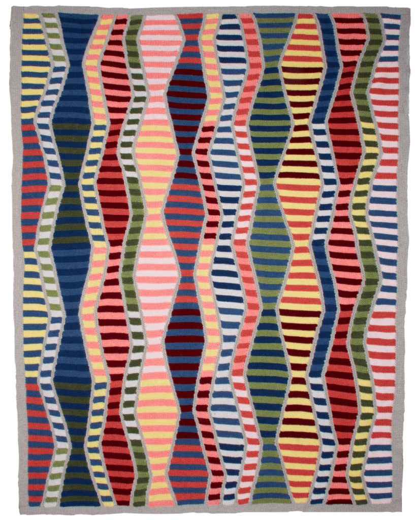 A multicolored, knitted blanket featuring geometric shapes. Stitches in Time, is a design by Margaret Holzmann.
