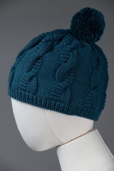 A blue knitted on a white mannequin head against a gray background