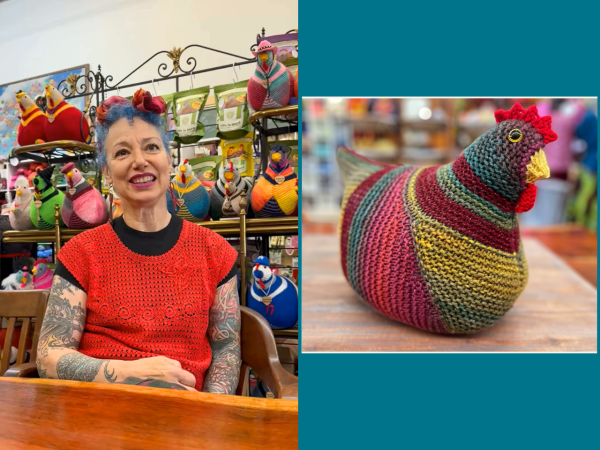 Store owner Annette Corsino-Blair sits behind a wooden table on the right, and one of her Emotional Support Chicken designs is featured on the right.